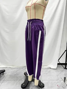 Purple Y2K high-waisted athletic track pants featuring white side stripes and drawstring.