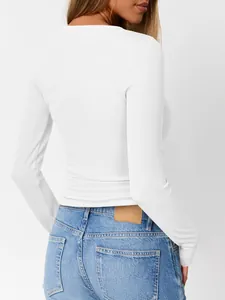 Back view showing the fit of a white ribbed long sleeve slim top with blue jeans.
