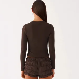 Back view of a minimalist dark brown rib-knit long sleeve top and matching ruffled shorts.