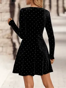 Back view of black velvet mini dress with rhinestone polka dots and long sleeves.