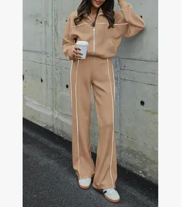 Femme en ensemble de survêtement beige deux pièces avec fermeture éclair et passepoil blanc