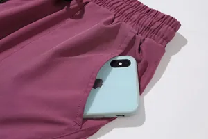 Close-up detail of a deep side pocket on women's purple quick-dry yoga pants with a phone.