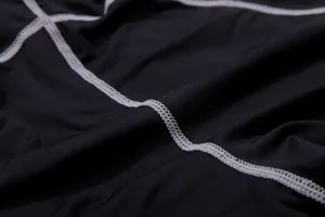 Detailed view of grey flatlock stitching on black quick-dry compression fitness fabric