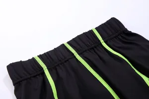 Close-up view of elastic waistband with lime green stitching on black compression leggings
