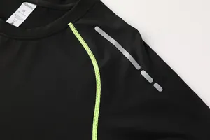 Dettaglio maglia sportiva nera con cuciture verde lime e striscia catarifrangente