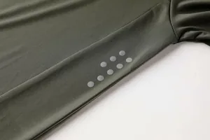 Detailaufnahme der reflektierenden silbernen Punkte auf dem olivgrünen Sportshirt-Ärmel