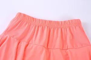 Close-up of coral sports tennis skort showing high-elastic waistband and quick-dry fabric.