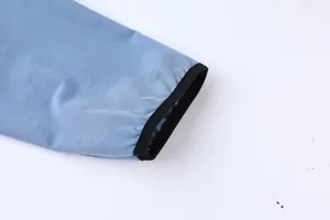 Primer plano detallado del puño elástico negro de una chaqueta deportiva azul para hombre