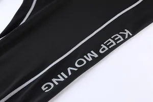 Close-up detail of black athletic leggings featuring KEEP MOVING slogan and white seams