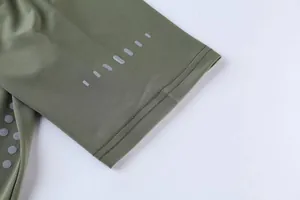 Close-up of olive green athletic shirt sleeve with reflective dots and fine stitching