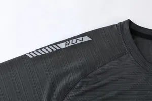 Close-up detail of reflective RUN logo and stripe pattern on shoulder of sports t-shirt