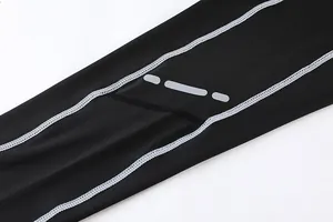 Dettaglio dei leggings a compressione sportivi neri con cuciture bianche e striscia riflettente