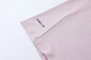 Gros plan sur la texture du tissu à séchage rapide et le logo PWRRUN+ sur haut de sport rose