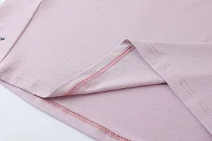 Gros plan sur l'ourlet d'un t-shirt de sport rose pour homme, montrant la texture en maille.