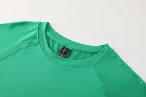 Close-up detail of the crew neckline and size tag on a green quick-dry athletic shirt