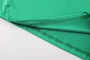 Detailed close-up of professional stitching on a green quick-drying sports compression shirt.