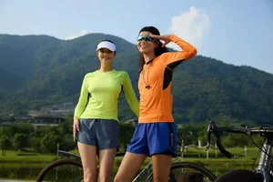 Two women wearing neon yellow and orange long-sleeve quick-dry athletic tops while cycling