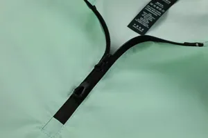 Close-up of a black zipper and care label on a mint green men's outdoor sports top