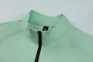 Close-up of mint green men's half-zip athletic top featuring stand collar and zipper detail.