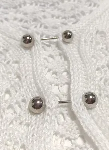 Macro detail view of white crochet beach cover-up featuring silver metal barbell closures.