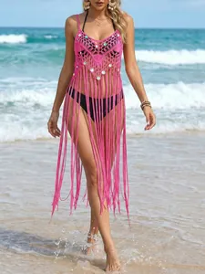 Häkel-Bikini-Cover-up in Pink mit Pailletten und langen Fransen am Strand getragen.