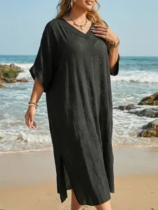 Detailansicht eines lockeren schwarzen Strandkleides mit V-Ausschnitt und Seitenschlitzen.