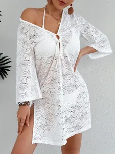 Detalle de un vestido de playa de ganchillo blanco con escote en V profundo y lazo frontal.