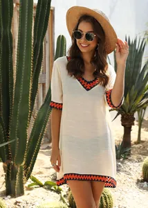 Elegant cream V-neck beach cover-up with vibrant orange crochet trim and boho details