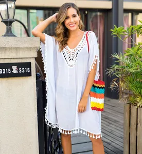 Detail of white crochet tassel beach cover-up on model in outdoor setting.