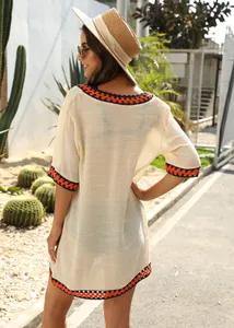 Detailed back view of a beige crochet beach cover-up with orange and navy trim.