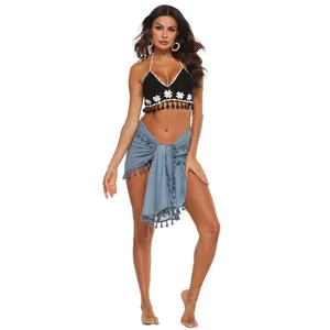 Detailansicht eines blauen Fransen-Sarongs mit einem schwarzen Häkel-Bikini-Top