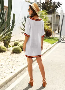 Back view of white crochet V-neck beach cover-up with contrast trim in outdoor resort setting