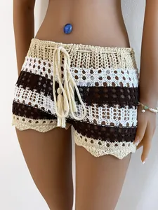 Detailed view of crochet knit beach shorts featuring tassel drawstring and color block stripes