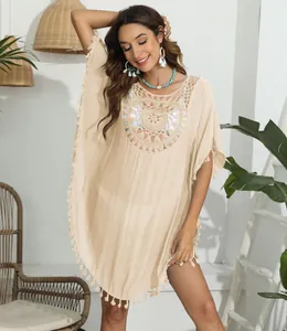 Ganzkörperansicht eines Boho-Häkel-Strand-Bikini-Cover-ups mit Quasten an einem lächelnden Model