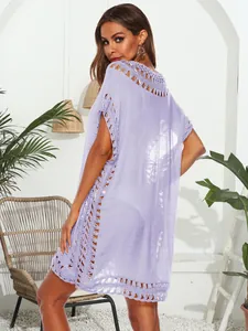 Vestido playero lila con cuello en V y detalles de ganchillo, mostrado por una modelo en patio