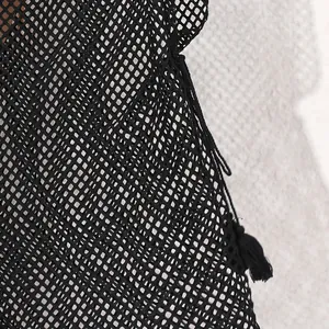 Close-up detail of black mesh beach cover-up showing intricate fishnet texture and tassel