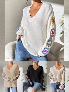 Détail d'un pull à col en V avec patchwork au crochet coloré sur les manches en couleurs.