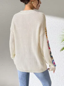Détail d'un pull en maille blanc oversize avec des manches fleuries en crochet coloré.
