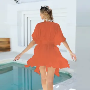 Vista trasera de una túnica de playa naranja vibrante con dobladillo de volantes en la piscina