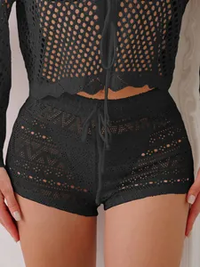 Detailed macro view of black hollow crochet lace beach shorts featuring a drawstring waist