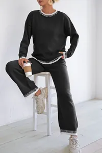 Detail view of a black two-piece knit set with white contrast stitching on a model