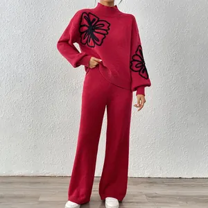 Detail view of red knit sweater set with black flower embroidery and wide-leg pants