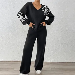 Detailed shot of a black knitted sweater set featuring white floral ribbon embroidery