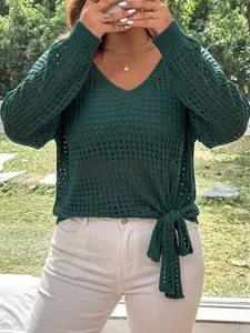 Detail showing the intricate pointelle knit texture and side tie knot of the green sweater
