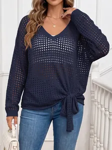 Detailed shot of a navy blue V-neck crochet sweater with a knot hem detail.