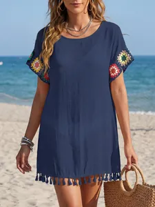 Detailansicht des marineblauen Strandkleids mit Häkelblumen-Ärmeln und Quastensaum-Saum.
