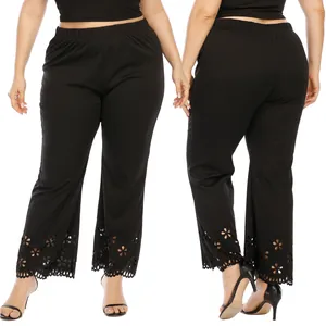 Detailed view of plus size black straight trousers with laser-cut floral hem patterns