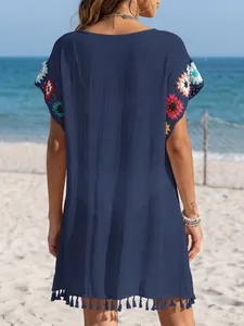 Marineblaues Strandkleid mit bunten Häkelblumen und Fransen, Rückansicht am Strand