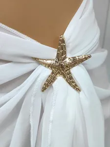 Close-up of gold starfish metal accessory on a white chiffon beach sarong skirt
