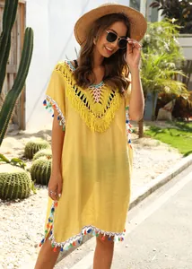 Yellow beach cover-up featuring crochet V-neck and colorful tassels for a bohemian summer look.